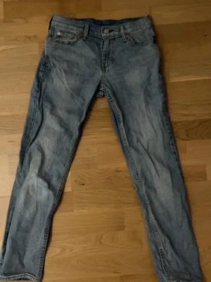 Levi's 511 ljusblå jeans W27 L29 - Säljer ett par klassiska Levi's 511 jeans i ljusblå denim. Modellen har smal passform och normal midja, med fem fickor och dragkedjegylf. Perfekta för en avslappnad och trendig look. Ikonisk läderpatch bak och snygga sömmar.