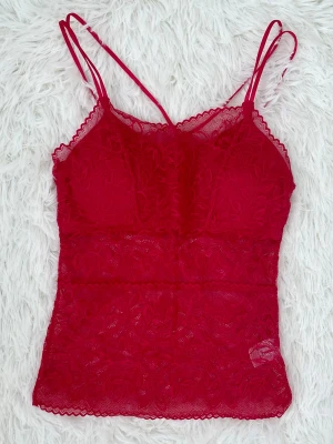 Röd spetsbody med tunna axelband - Snygg röd body i spets med tunna axelband och inbyggda kupor. Storlek: S (36), byst under 88cm, midjan under 70cm.
