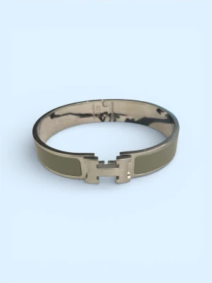 H Click armband khaki - Snyggt armband i metall med khakigröna emaljdetaljer och det ikoniska H-spännet framtill. Armbandet har en stilren och modern design som passar perfekt till din vardagsstil. Lätt att öppna och stänga med det klassiska klicklåset.