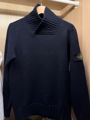 Stone Island tröja - Mörk marinblå stickad Stone Island tröja i premiumkvalitet. Stilren design med hög ribbad krage och ikonisk kompasspatch på vänster ärm. Tjock och lyxig stickning som ger en exklusiv känsla. Märkt storlek XL men passar som S. ✨