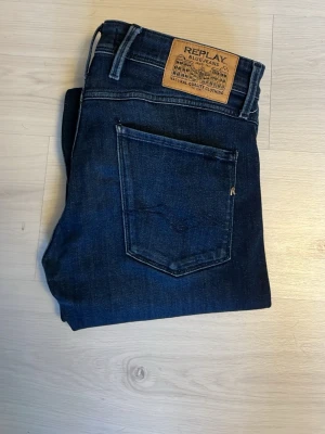 Replay jeans - Snygga mörkblå jeans från Replay med klassisk femficksdesign och läderpatch bak i midjan. Jeansen har raka ben och är tillverkade i ett slitstarkt denimtyg som ger en tidlös look. Perfekta för dig som gillar stilrena och bekväma jeans. Storlek 30/30 anbass slimfit