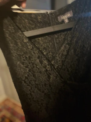 Svart spetsklänning från Ax Paris - Säljer en svart klänning från Ax Paris med v-ringning och vacker spetsdetalj. Klänningen har omlott-design och är perfekt för dig som gillar en elegant och stilren look. Passar till många olika tillfällen och är riktigt snygg att styla med klackar.