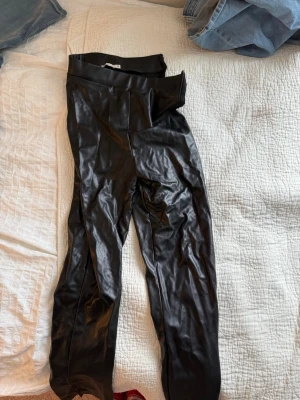 Svarta fuskskinnleggings från NLY Trend - Säljer ett par svarta leggings i fuskskinn från NLY Trend, storlek XS. De har hög midja och en glansig finish som ger en cool look. Perfekta att styla med oversized tröja eller crop top. Materialet är stretchigt och mjukt på insidan.
