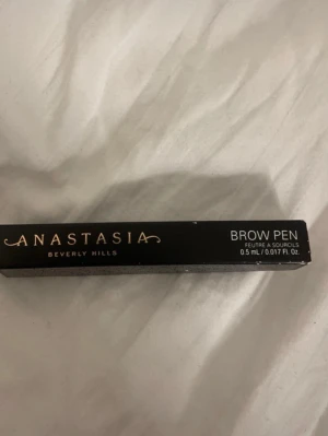 Anastasia Beverly Hills Brow Pen - Snygg och smidig ögonbrynspenna från Anastasia Beverly Hills. Pennan har en tunn spets för exakt applicering och kommer i en svart förpackning med stilren design. Perfekt för att skapa naturliga och definierade bryn. Innehåller 0,5 ml.