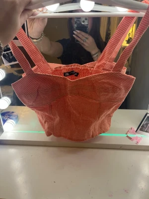 Rutig röd korsettopp från Zara - Supersöt röd och vit rutig korsettopp från Zara med breda axelband och smockad rygg. Toppen har en figurnära passform och är gjord i bomull, perfekt för sommarens alla outfits.                        Priset kan diskuteras vid snabb affär💗