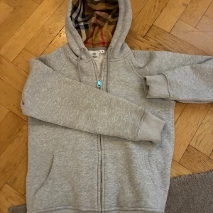Grå ”Burberry hoodie”  - Snygg grå hoodie med dragkedja och klassiskt Burberry-mönster i huvan. 