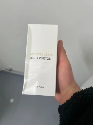 Louis Vuitton Rose Des Vents parfym -  Louis Vuitton Rose Des Vents – helt ny och oöppnad. En elegant och exklusiv Eau de Parfum med mjuka rosnoter, frisk pion och en lätt, pudrig värme som gör doften både feminin och lyxig. Levereras i original, vit LV‑kartong med guld- och svart text. Perfekt för dig som vill ha en äkta, fransk premiumdoft i nyskick.