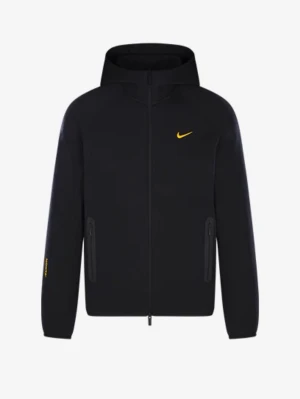 Svart Nike nocta  - Snygg svart hoodie från Nike med dragkedja och huva. Den har en gul Nike-logga på bröstet och diskreta gula detaljer på ärmen och ryggen. Två fickor med dragkedja framtill. Perfekt för en sportig och avslappnad stil.