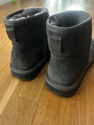 Mörkgråa uggs liknande skor - Uggs liknande skor i fint skick. Köpt för ett par år sen men knappt använda. Fortfarande lurviga inuti. Storlek 39 men skulle säga att de är 38