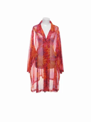 Transparent blommig tunika i orange och rött - Blus i transparent material med blommigt mönster i orange, rött och rosa. Modellen har lång ärm, klassisk krage och knappar framtill. Perfekt för lager på lager och ger en färgstark vibe till din outfit.