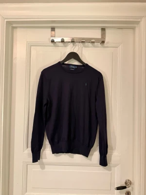 Merino tröja Polo Ralph Lauren storlek S - Väldigt fin Merino stickad tröja från polo Ralph lauren passar som S men storleken i tröjan är XL. Den är mörkblå i ljus men nästan svart när det inte är direkt ljust. Tröjan är i 100% italiensk merino. Det är normal till smal passform