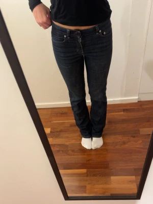 Mörkblå bootcut jeans från Filippa K - Säljer ett par mörkblå straight jeans med låg midja ifrån Filippa K. Jeansen har kontrastsömmar och är tillverkade i ett stretchigt denimtyg som sitter snyggt på benen. Perfekta för en avslappnad och trendig look. Dem är i storlek 28/34 som är en S skulle jag säga 