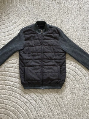 Grå cardigan Helt ny  - Helt ny endast använd 2 gång Snygg grå cardiganjacka från LC med quiltad front och stickade ärmar. Jackan har dragkedja, ribbad krage och muddar samt två stora fickor framtill. Perfekt för lager-på-lager och en stilren look. Köptes för 1900kr 