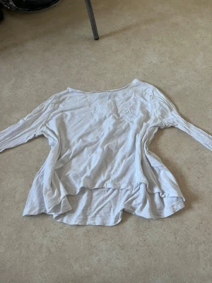 Vit långärmad topp i bomull - En basic vit långärmad topp med rund hals och lös passform. Har små små hål men inget man lägger märke till. 