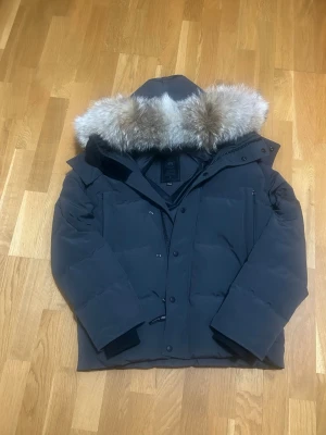 Svart dunjacka från Canada Goose - Säljer en svart dunjacka från Canada Goose med stor huva och avtagbar pälskant. Jackan har flera fickor, diskret logga på ärmen och kraftig dragkedja med knappar. Perfekt för kalla vinterdagar och riktigt varm. Samt en nfc scan! KAN GÅ NER I PRIS VID SNABB AFFÄR!!!