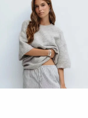 Grå stickad kortärmad tröja från Gina - Grå stickad tröja från Gina med korta ärmar och rund halsringning. 