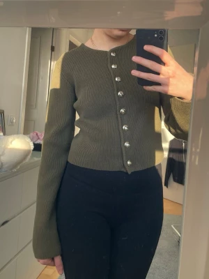 Olivgrön ribbad kofta med pärlknappar - Jättefin långärmad tröja med guldknappar. Köpt från Hm. Oanvänd och prislapp hänger kvar