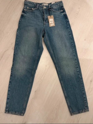 Blå mom jeans från Denim Project - Säljer ett par klassiska blå mom jeans från Denim Project. Jeansen har hög midja, 