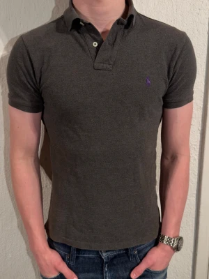 Mörkgrå piké från Ralph Lauren - Säljer en mörkgrå pikétröja från Ralph Lauren. Den är använd men inga defekter. Storlek s men passar även xs. Modellen är 180 och väger 70kg. Hör av er vid fundering eller frågor😊✌️