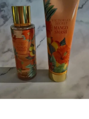 Victoria's Secret Mango Smash parfymset - Fräscht parfymset från Victoria's Secret i doften Mango Smash. Setet innehåller en body mist och en body lotion, båda i färgstarka orange och guldiga förpackningar med tropiska blommor och mangomotiv. Perfekt för dig som älskar fruktiga och exotiska dofter. Helt nytt och oanvänt