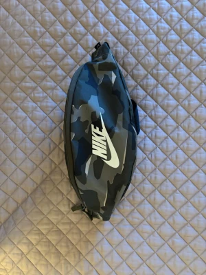 Nike axelremsväska  - Säljer nu min nike axelremsväska då jag inte använder den! | Bra skick som ni ser på bilderna. | Kan användas till magen eller bakom ryggen! | One size. | Cool camo färg. | Släng iväg en signal vid funderingar så svarar jag snabbt. | 