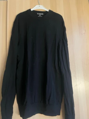 Svart slim fit tröja från H&M - En svart långärmad tröja från H&M i slim fit-modell. Tröjan har rund halsringning och är tillverkad i ett mjukt material som passar perfekt till en avslappnad stil. Enkel och stilren design som funkar året runt.