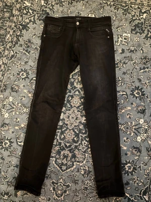Svarta Replay jeans - Svarta Replay Anbass jeans. Byxorna är i bra skick och är knappt använda. Storlek 31/34. Hör av er om det finns några frågor!