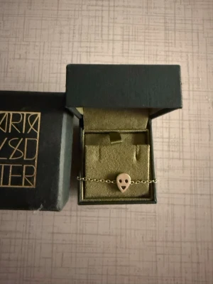 Armband från Maria Nilsdotter - Snyggt armband i silver från Maria Nilsdotter. Kedjan är tunn och elegant, och dödskallen har en stilren design i metall. Perfekt accessoar för dig som gillar unika smycken med edge. Skriv vid intresse