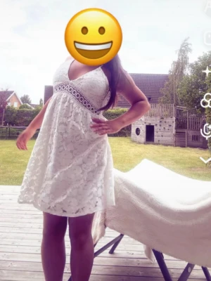 Vit spetsklänning med v-ringning och öppen rygg - Söt vit kortklänning med v-ringad hals och bred spetsdetalj under bysten. Klänningen har tunna axelband och är ärmlös samt har en öppen rygg.  Perfekt för sommarens alla tillfällen. Denna klänningen är köpt i Italien i en liten butik. Använd en gång endast på midsommar. Jag är en 1,50 så klänningen är lite lång på mig som ni ser men den ska egentligen vara kortare. Den är stor i storlek så skulle säga den passar någon i S kanske till och med M. 