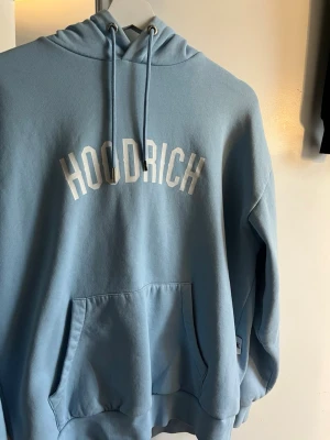 Blå hoodie från Hoodrich XS - Snygg ljusblå hoodie från Hoodrich med vit logga tryckt över bröstet passar både för män å kvinnor pris kan diskuteras vid snabb affär 