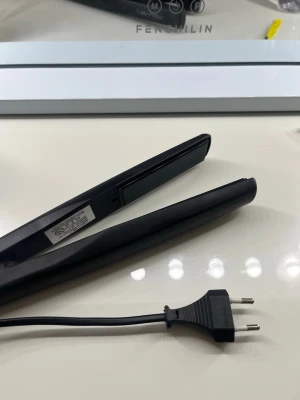 Svart plattång från Waves - En stilren svart plattång från Waves med slät design och keramiska plattor. Perfekt för att styla håret rakt eller skapa lockar. Utrustad med sladd och europeisk kontakt. Enkel att använda och passar de flesta hårtyper. Går tyvärr inte att ändra värmen på och lite slitage på ena plattan men funkar som vanligt.