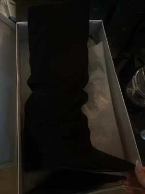 Svarta folded boots Nelly  - Säljer ett par oanvända folded boots ifrån Nelly. Stövlarna har en mjuk mocka-liknande yta och en trendig, rynkad design som ger en avslappnad men ändå edgy vibe. Perfekta att styla till både jeans och kjol.