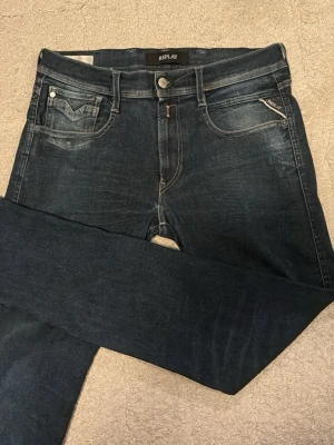 Replay anbass  - Snygga mörkblå jeans från Replay i modellen ambassador med klassisk femficksdesign och diskreta snygg slitningar. Jeansen har en slim fit och detaljerade sömmar på bakfickorna. Perfekta för dig som gillar en stilren och tidlös look. W31 L32