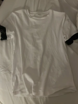 Vit t-shirt med spetsdetalj - Snygg vit t-shirt med korta ärmar och svarta spetsdetaljer längst ut på ärmarna. Köpte den på zara för 200kr men har aldirg kommit till användning då jag har liknande tröjor 