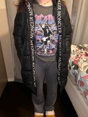 Svart lång dunjacka från Moncler - Säljer en svart lång dunjacka från Moncler med huva och dragkedja framtill. Jackan har stora fickor och Moncler-logga på insidan av huvan. Perfekt för kalla vinterdagar och riktigt snygg streetstil.