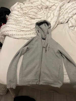 Ljusgrå hoodie från Sali racing  - Snygg ljusgrå hoodie från sail racing med dragkedja framtill, huva med dragsko och en bröstficka med dragkedja. Perfekt för en avslappnad och stilren look. Tillverkad i mjukt material för extra komfort.