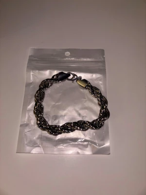 Cordell armband (Silver 10mm 20cm) - Snyggt armband med tvinnad kedja i silverfärgad metall. Armbandet har en robust karbinhake och en stilren design som passar perfekt till streetwear och trendiga outfits. Perfekt accessoar för dig som gillar en clean och modern look.