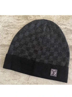  svart rutig mössa - Snygg svart mössa från  med diskret rutmönster och vikt kant. Märkets klassiska  sitter på en patch framtill. Perfekt accessoar för dig som gillar exklusiv streetstyle. Materialet ser ut att vara mjukt och bekvämt, troligen ullblandning.