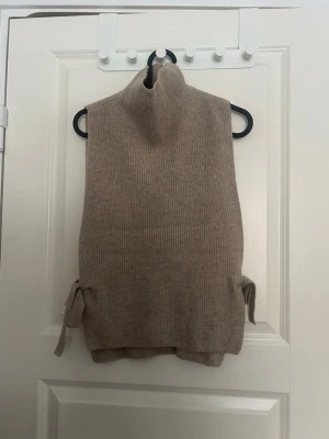 Virkad polo topp - Beige virkad polo väst/tröja från Arket i 100% ull, öppen på sidorna med knyten. Onesize men passar S bäst 