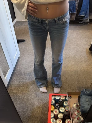 Ljusblå bootcut jeans  - Säljer ett par ljusblå bootcut jeans från gina young med klassiska kontrastsömmar och stenar på bakfickor. Jeansen har låg midja och fem fickor, perfekta för en avslappnad och trendig look. S 14+.