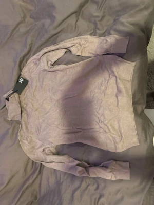 Ljuslila stickad polotröja från H&M - Säljer en ljuslila stickad polotröja från H&M. Tröjan har långa ärmar, ribbstickade muddar och hög krage. Perfekt för lager-på-lager och enkel att matcha med jeans eller kjol.