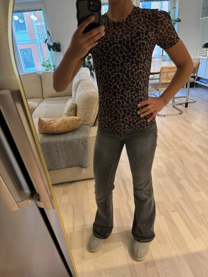 Leopardmönstrad tight topp - Säljer en tight topp med leopardmönster i bruna och svarta toner. Toppen har korta ärmar och rund halsringning. Perfekt för dig som vill sticka ut med ett djuriskt print. Materialet känns mjukt och stretchigt, troligen polyester eller bomullsmix. Den är lite halvt genomskinlig💕