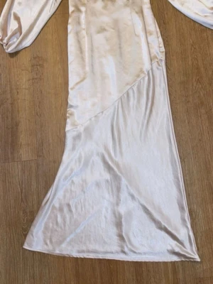 Boohoo maxiklänning  - Elegant långklänning i skimrande champagnefärgad satin med långa puffärmar och urringning i ryggen. Endast använd en gång, mycket fint skick. 