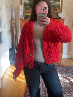 Röd stickad kofta med knappar❤️ - Säljer en chunky röd stickad kofta med stora bruna knappar framtill. Koftan har långärmad design, bred ribbstickning och en kortare passform. 