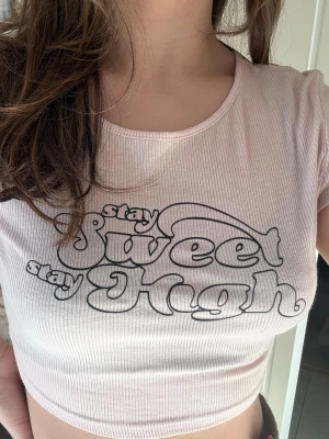 Ljusrosa topp - H&M  - Trendig ljusrosa croppad topp med ribbad struktur och svart texttryck 'stay sweet stay high' framtill. Knappt använd, från H&M