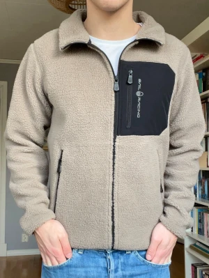 Sail Racing fleecejacka beige – storlek S - Snygg Sail Racing fleece i beige med svart bröstficka. Väldigt skön och varm jacka som funkar perfekt höst/vår eller som mellanlager.  Bra skick.  Storlek S men passar även en mindre M beroende på passform.  Nypris ca 1500 kr.