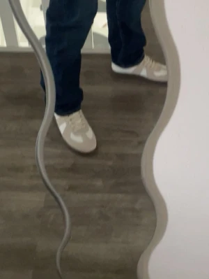 Vita gats - Snygga sneakers i beige och vitt med klassisk snörning. Skorna har en stilren design och passar perfekt till jeans eller andra avslappnade outfits. Materialet ser ut att vara en mix av skinn och syntet för en modern look.