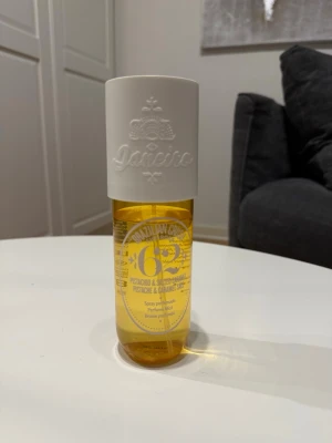 Sol de Janeiro Brazilian Crush 62 - En snygg parfymmist från Sol de Janeiro med doft av pistage och salt karamell. Flaskan är genomskinlig gul med en stor vit kork där märket är präglat. Perfekt för dig som gillar söta och fräscha dofter.