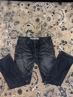 Mörkblå jeans från Timezone - Säljer ett par mörkblå jeans från Timezone Denim Inc. Jeansen har klassisk femficksmodell, raka ben och snygga slitningar framtill. Tillverkade i slitstark denim med detaljerade sömmar och metallknappar. Perfekta för en avslappnad och cool stil.