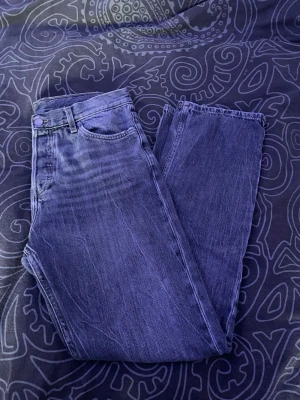 Grå raka jeans från weekday 29/32 - Säljer ett par grå jeans med rak passform och klassisk femficksdesign. Jeansen har en snygg tvättad look med subtila slitningar och är tillverkade i denim. Perfekta för dig som gillar en avslappnad och tidlös stil.